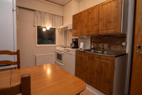 a kitchen with wooden cabinets and a wooden table at Mission Guesthouse in Gäddnäs