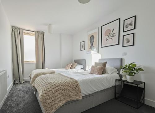 two beds in a bedroom with white walls at Luxury cosy apartment with stunning London skyline views! in London