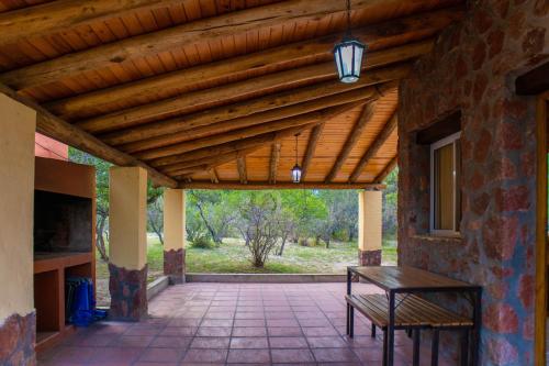 a patio with a wooden roof with a table and a bench at Cabañas en Nono La Soñada in Nono