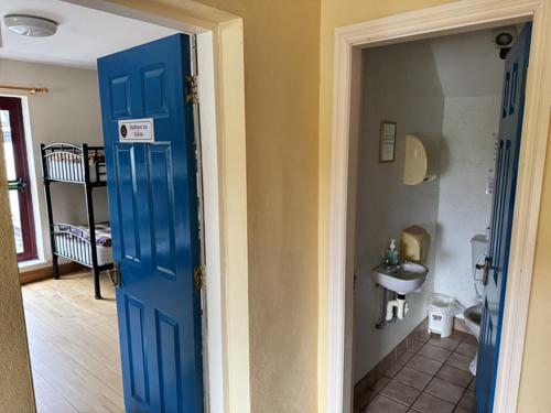 Una puerta azul que conduce a un baño con lavabo. en Brú na Dromoda/Dromid Hostel, en Killeenleagh Bridge