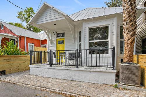 a white house with a black fence in front of it at Haven Tiny House - Pool, Walk to Downtown in St. Augustine