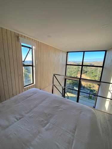 um quarto com uma grande cama branca e grandes janelas em Refugio Matanzas Loft con Jacuzzi privado em Pupuya