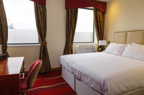 a hotel room with a bed and a desk and window at ICON Hotel in Luton