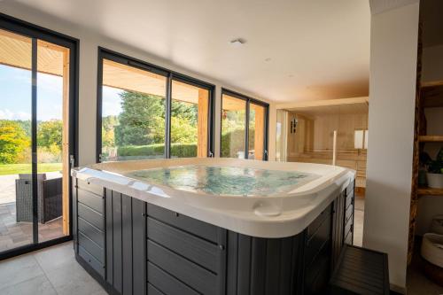 a large bath tub in a room with windows at Aux mélèzes de Xavier GÎTE 4 étoiles in Wangenbourg
