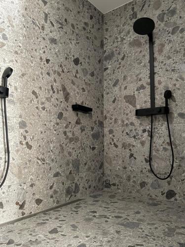 a bathroom with two shower heads on a stone wall at KaiserLogen Wellness in Kaisersesch
