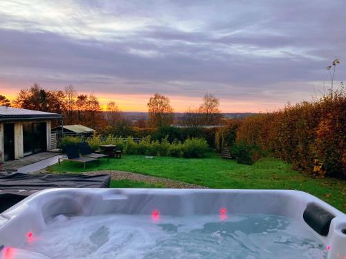 una bañera de hidromasaje en un patio con una puesta de sol en el fondo en Terrier Ovifat - Nature Jacuzzi & Sauna, en Ovifat