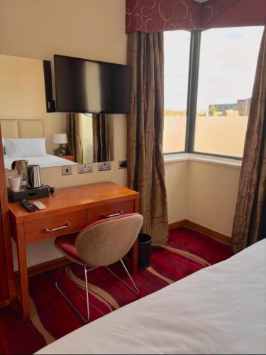a hotel room with a desk and a bed at ICON Hotel in Luton