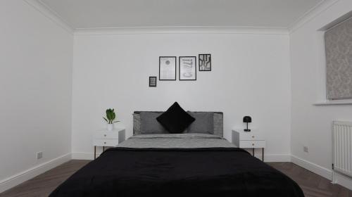 Un dormitorio blanco con una cama y dos mesitas de noche. en Modern 3 bed house in Edmonton with private driveway parking, en Edmonton