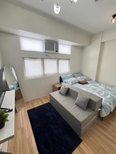 een slaapkamer met een bed en een bank bij Holly's Place by Motorists Transient House in Biñan