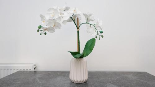 Un jarrón blanco con flores blancas sobre una mesa. en Modern 3 bed house in Edmonton with private driveway parking, en Edmonton