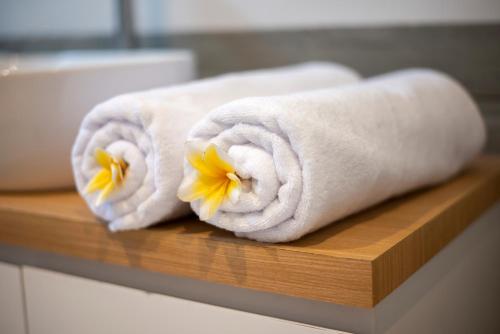 deux serviettes à fleurs sur une étagère en bois dans une salle de bain dans l'établissement Center of Canggu - cute little villa - calm & quiet, à Canggu