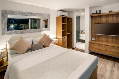 une chambre avec un grand lit et une télévision à écran plat dans l'établissement Center of Canggu - cute little villa - calm & quiet, à Canggu