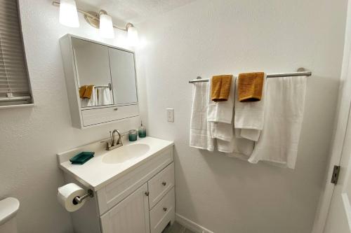 ein Badezimmer mit Waschbecken, Spiegel und Handtüchern in der Unterkunft Lilac Loft- Lake, Pool, Pickle Ball, Disney, Fun! in Castle Hill