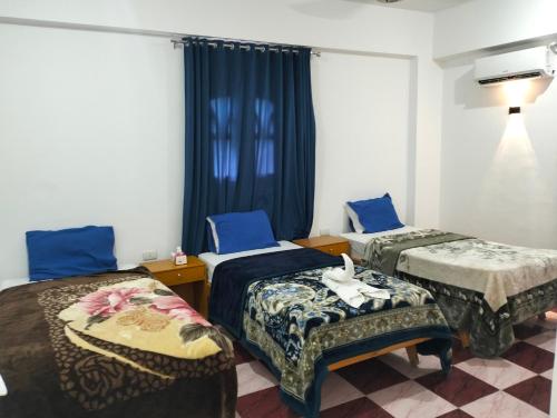 Dos camas en una habitación con cortinas azules. en Djorff Guest House, en Luxor
