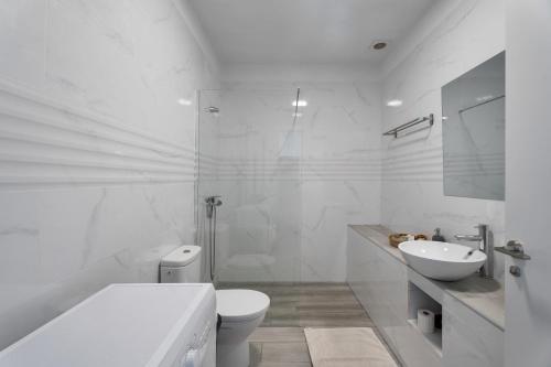 een witte badkamer met een toilet en een wastafel bij 4 Apartamentos Omanai Tenerife Sur in Las Galletas