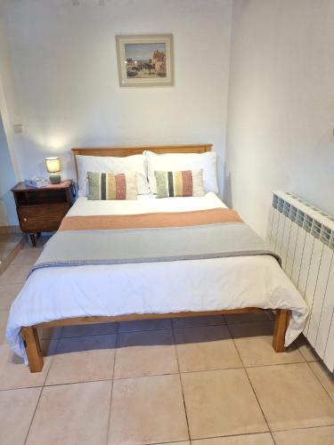 un grand lit dans une chambre avec une table de nuit dans l'établissement Le Clairat, à Saint-Michel-Saint-Jaymes