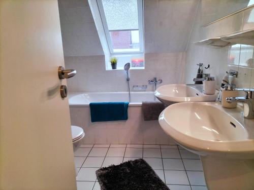 a bathroom with two sinks and a tub and a toilet at Meeresfeeling in Horumersiel in Horumersiel