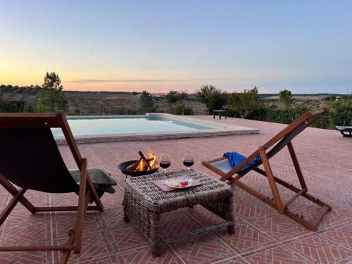 a patio with two chairs and a fire pit with wine glasses at Courela da Azinheira - Country Guesthouse in Lavre
