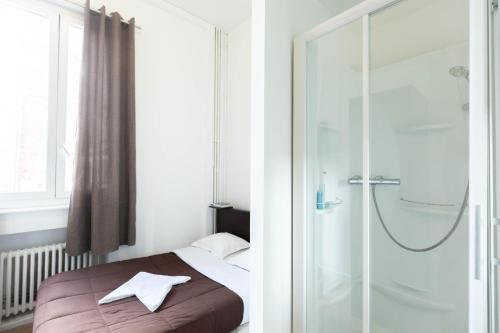 a bedroom with a bed and a glass shower at Hôtel Le Paris Brest in Lens