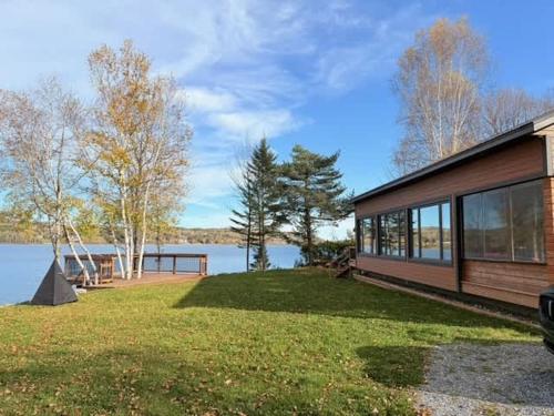a house on a lawn next to a body of water at Le Domaine Riverin in Pohénégamook