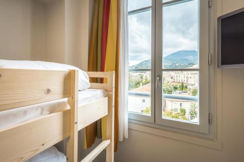 Dormitorio con ventana, cama y TV en Hôtel Miléade L'Orangeraie - Menton, en Menton