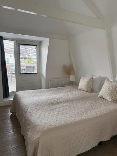 a white bed in a white room with a window at Koningshof XL in Alkmaar