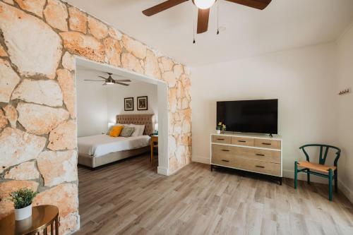 Dormitorio con pared de piedra, cama y TV en Guana Beach Inn, en Great Guana Cay