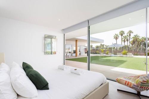ein Schlafzimmer mit einem weißen Bett und Blick auf einen Golfplatz in der Unterkunft Villa Palm Abama Golf in Playa de San Juan