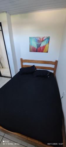 a bed in a bedroom with a painting on the wall at Kitnet in Itaparica Town
