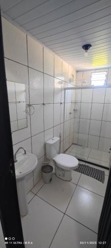 a white bathroom with a toilet and a sink at Kitnet in Itaparica Town