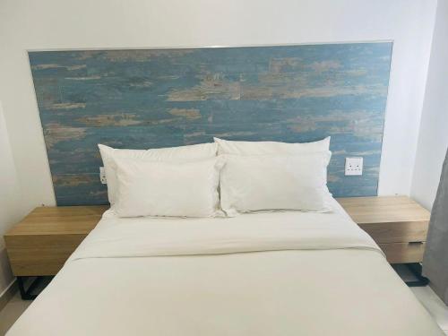een groot bed met witte kussens en een blauw hoofdeinde bij Canvas Lofts 2 – Famona duplex 2-bed - 2311 in Bulawayo