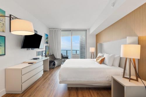 ein Schlafzimmer mit einem weißen Bett und einem großen Fenster in der Unterkunft Lyfe Resort Oceanfront Luxury Apartment - Exclusive Stay in Hollywood Beach in Hollywood