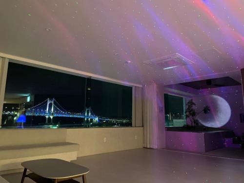 a room with a purple ceiling with a view of a bridge at 광안사계스테이 GwanganSagyeStay in Busan