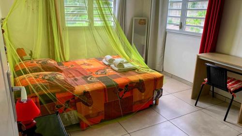 a bedroom with a bed with a colorful blanket at La Maison d'Abigaelle in Le François