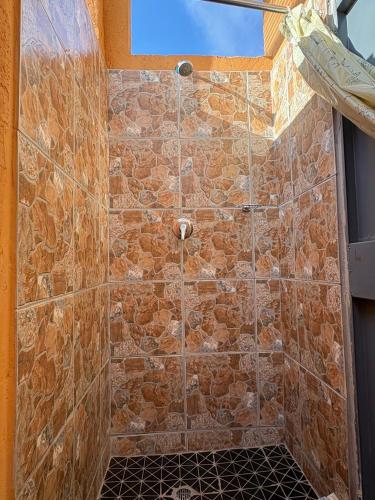 a bathroom with a shower with a stone wall at Shumba Camping Site in Mahikeng