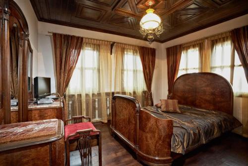 een slaapkamer met een bed, een tv en ramen bij Радева къща Жеравна in Zheravna