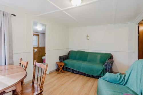 un soggiorno con un divano verde e un tavolo di 2-Bedroom Cottage #3 - Sugar Pine a Gravenhurst