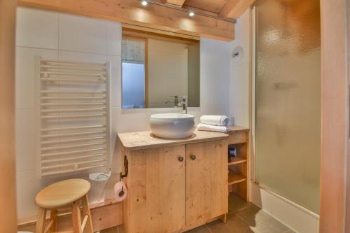 une salle de bain avec un lavabo et un comptoir avec un tabouret dans l'établissement Refuge Les Faitières F7, au Grand-Bornand