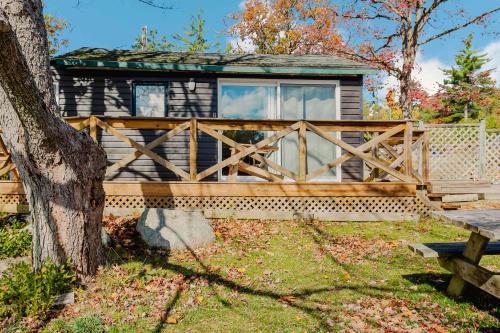 a log cabin with a wooden fence and a bench at Studio Cottage #8 - Jack Pine in Gravenhurst