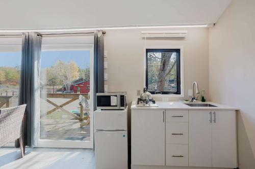 eine Küche mit einem weißen Kühlschrank und einer Mikrowelle in der Unterkunft Studio Cottage #8 - Jack Pine in Gravenhurst