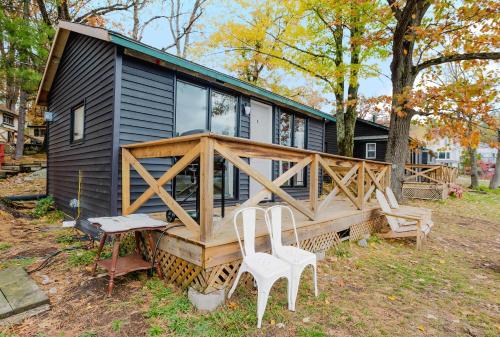 a black tiny house with two white chairs and a porch at Studio Cottage #9 - Virginia Pine in Gravenhurst