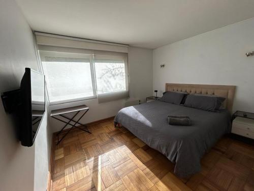 a bedroom with a bed and a flat screen tv at Bicentenario Park Apartment in El Cerrillo