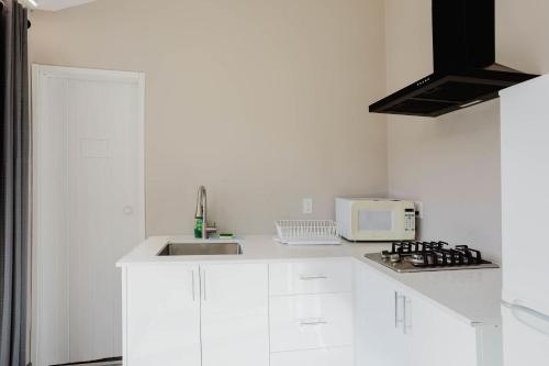eine weiße Küche mit Spüle und Mikrowelle in der Unterkunft 2-Bedroom Cottage #11 - Red Pine in Gravenhurst