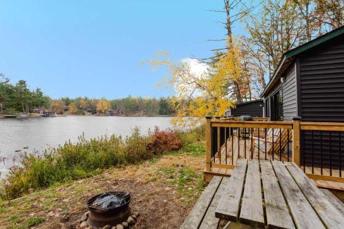 a cabin with a wooden deck next to a river at 2-Bedroom Cottage #11 - Red Pine in Gravenhurst