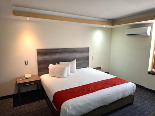 um quarto de hotel com uma cama grande e um cobertor vermelho em Hotel ALO! Express em Torreón