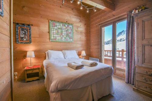 una camera da letto con un letto in una camera in legno con finestra di Chalet Berrier a Le Grand-Bornand