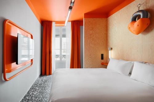 une chambre d'hôtel avec un lit et une télévision dans l'établissement Beauquartier - Chemin Vert, à Paris