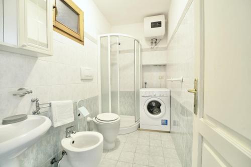 a bathroom with a toilet sink and a washing machine at Patresi Mare - Goelba in Mortigliano