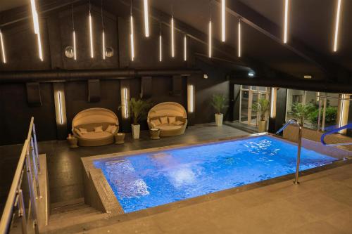 a swimming pool in a room with two chairs next to at Park hall Hotel & Spa Lancashire, a member of Radisson Individuals in Eccleston