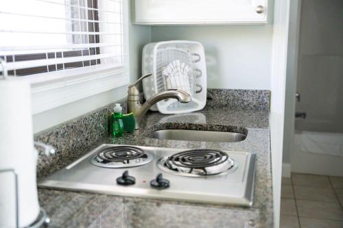 a kitchen counter with a sink and a stove at Surf & Sand Beach Motel in South Yarmouth